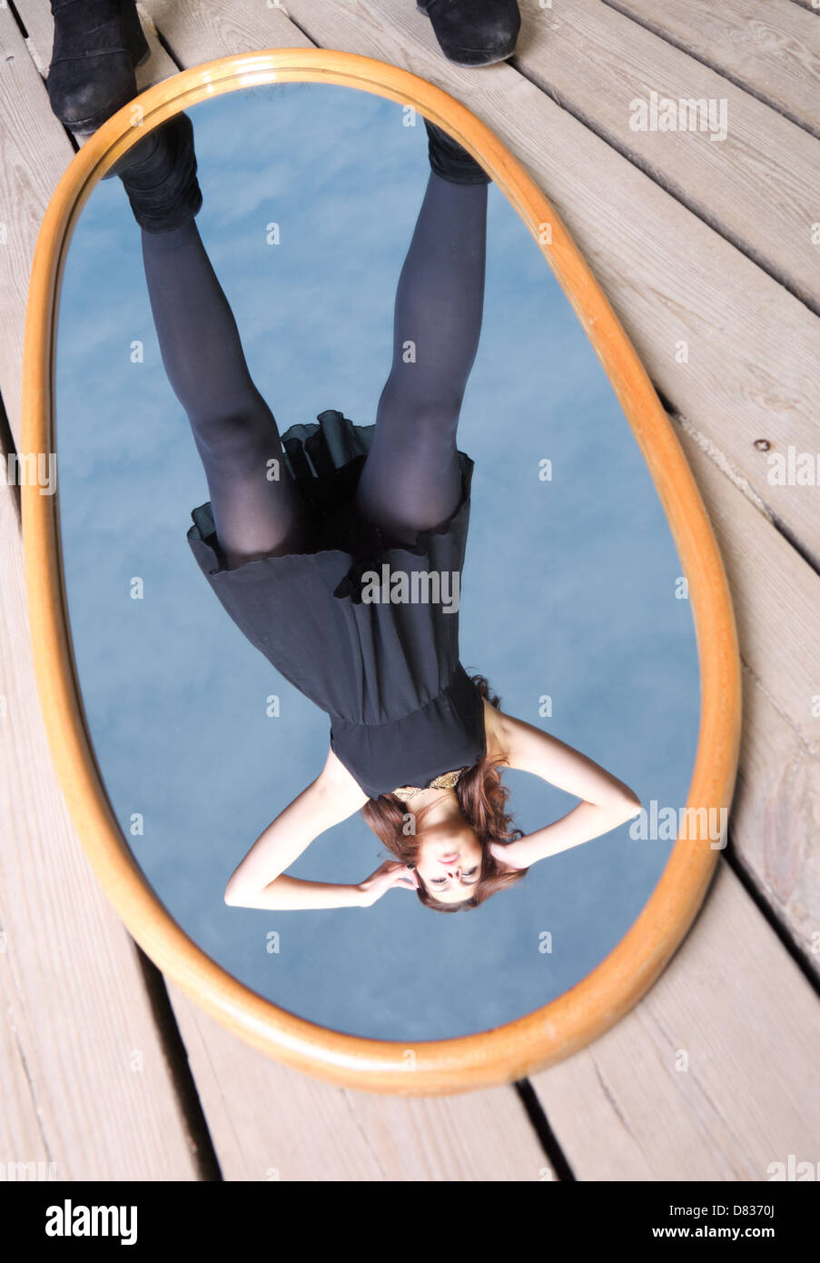 thoughtful young woman in black with her reflection in mirror - solitude lonely concept Stock Photo