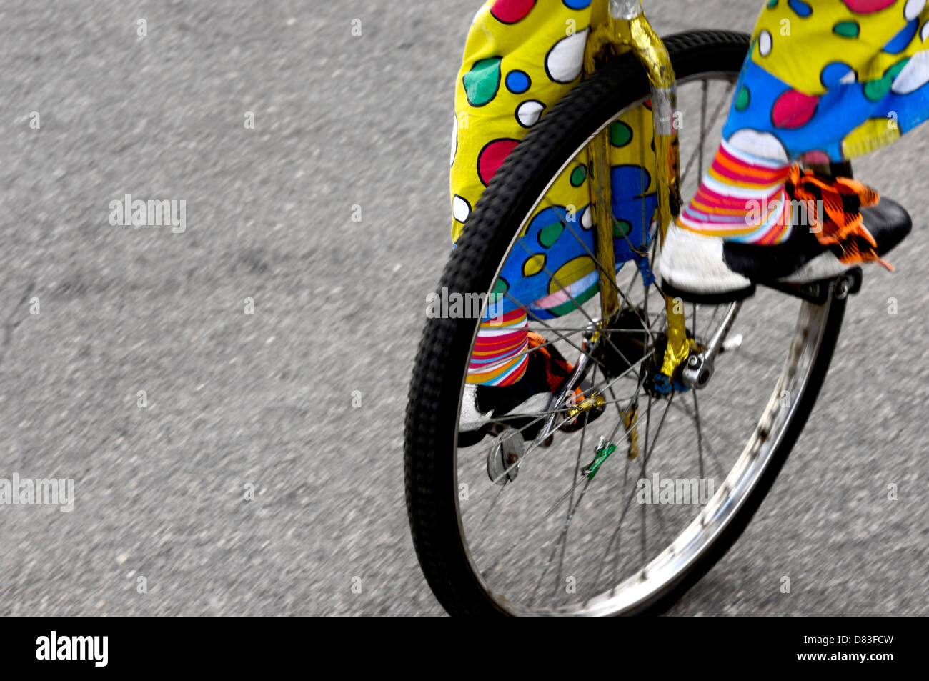 Clown riding a unicycle one wheeled bike on a street, closeup of legs Stock Photo