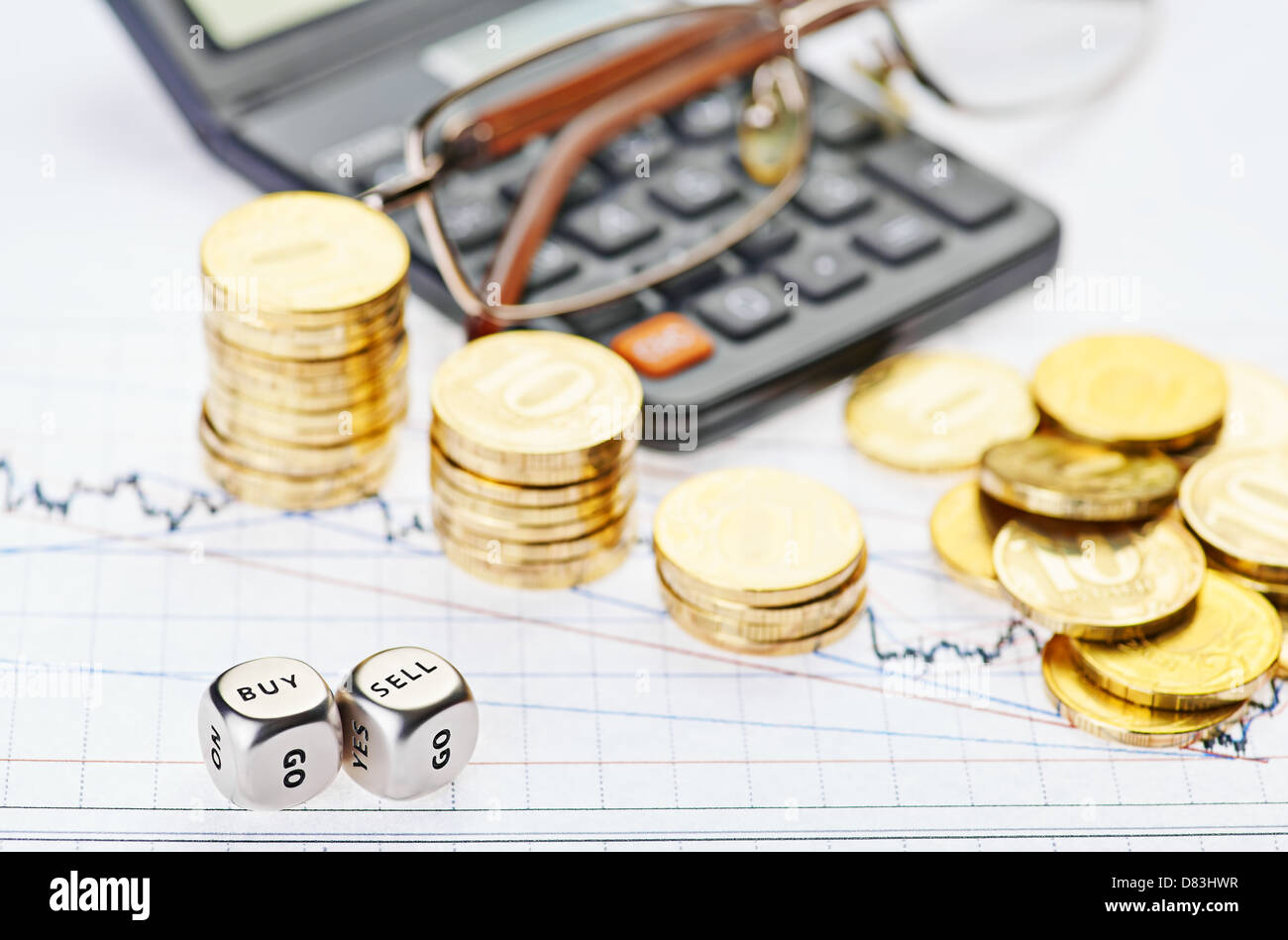 Downtrend stacks coins, calculator, glasses and dices cubes with the words SELL BUY on the financial stock charts. Stock Photo