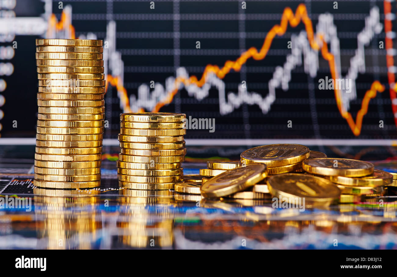 Downtrend stacks of golden coins and financial stock charts as background. Selective focus Stock Photo