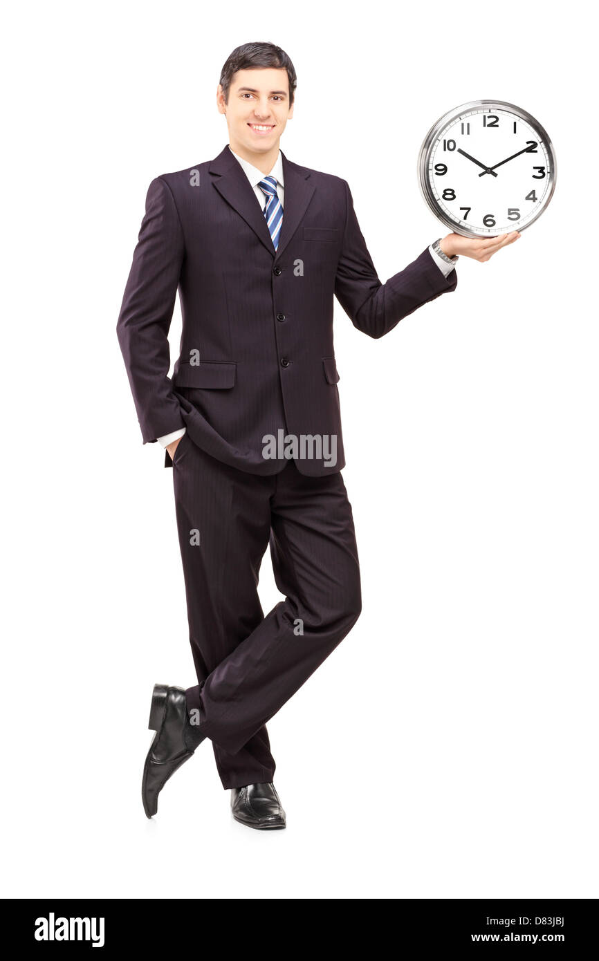 Full length portrait of a young man in suit holding a clock isolated on white background Stock Photo