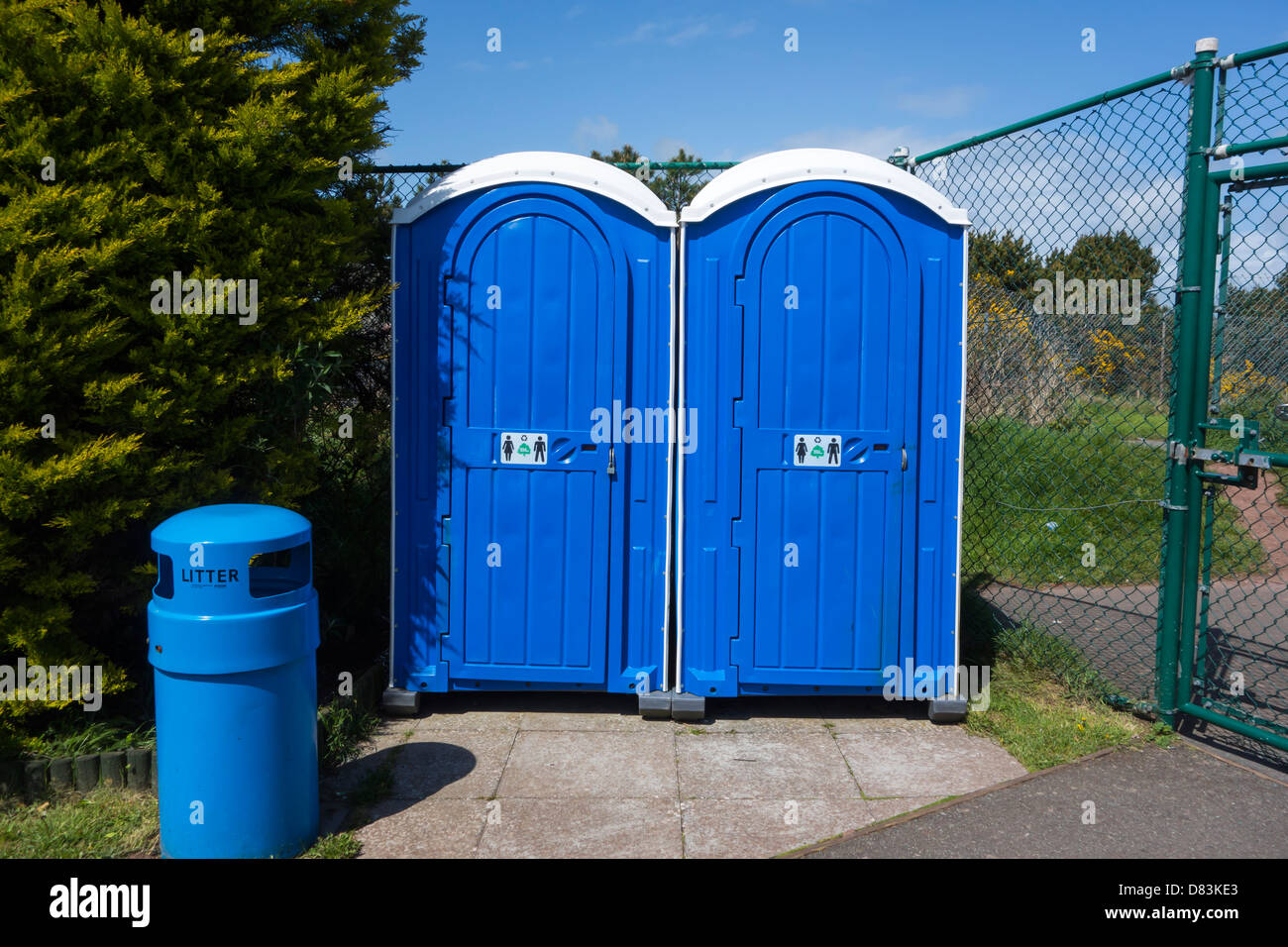 Pair of blue portable toilets and a blue litter bin. Stock Photo