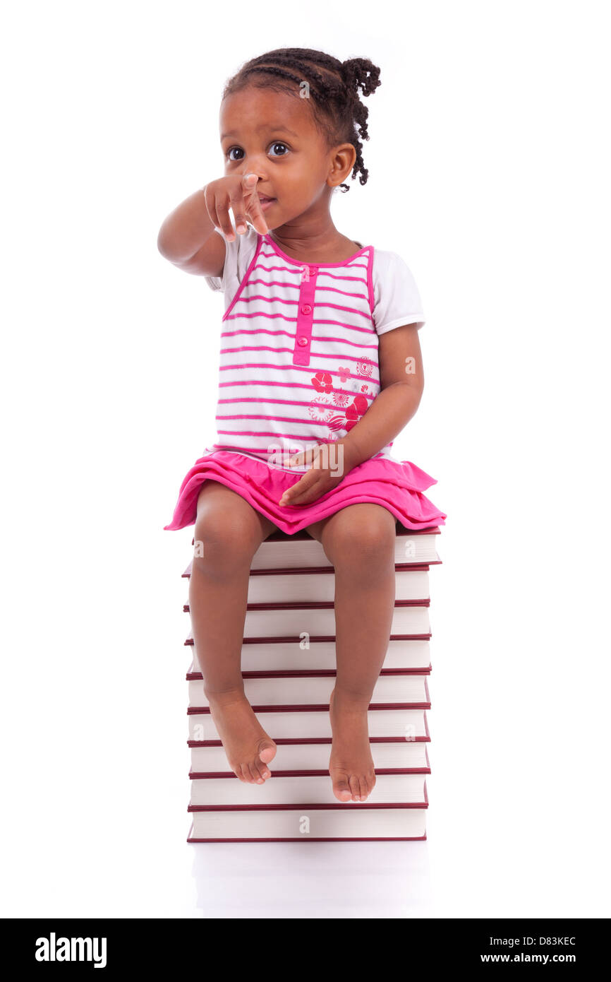 Cute black african american little girl seated in a stack of books, isolated on white background - African people - Children Stock Photo