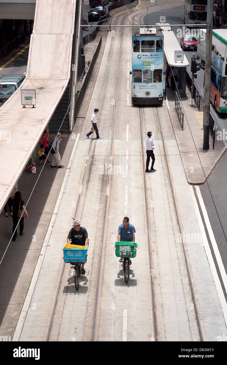 Bicycle delivery men riding along the tram tracks in the Wanchai