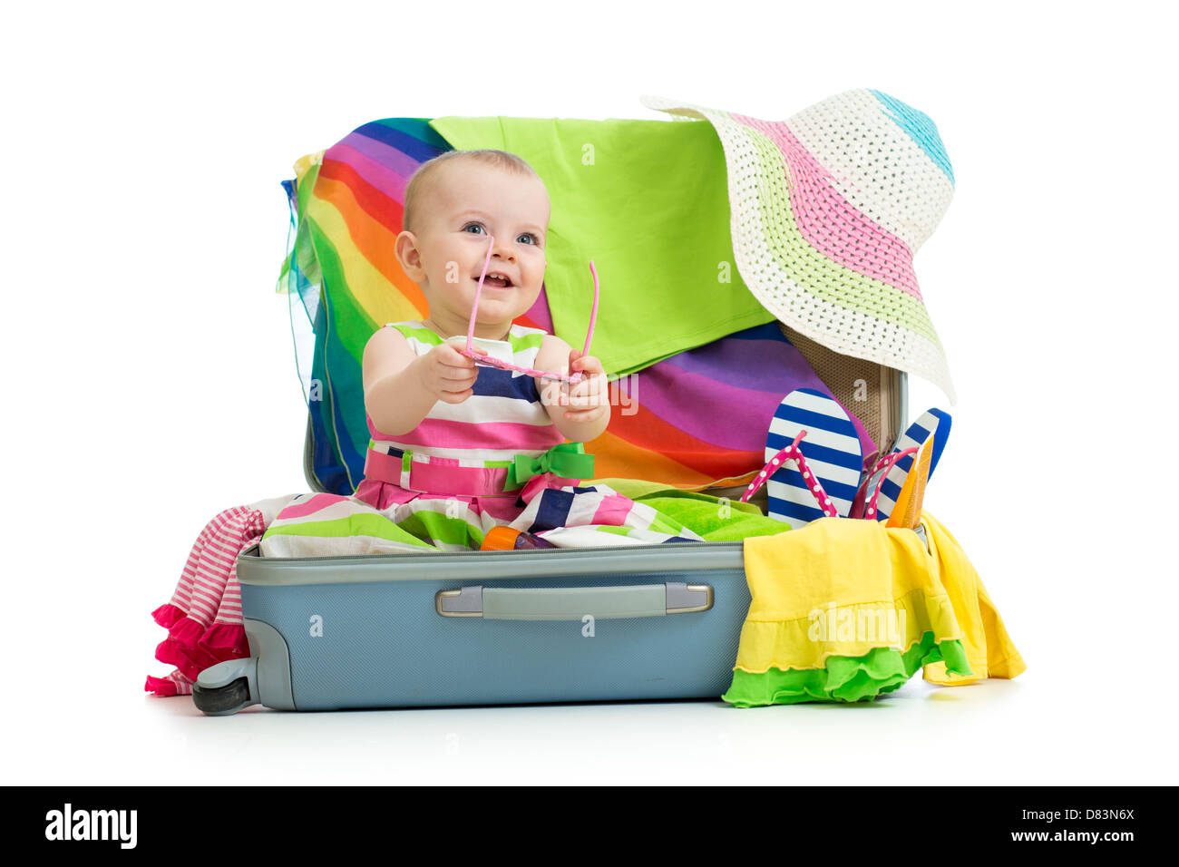 Baby girl sitting in suitcase with things for vacation travel Stock Photo