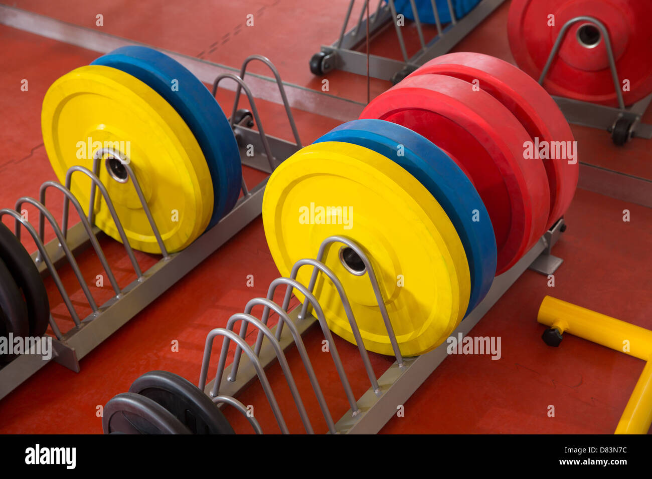 Crossfit fitness gym weight lifting bar colorful equipment on red floor