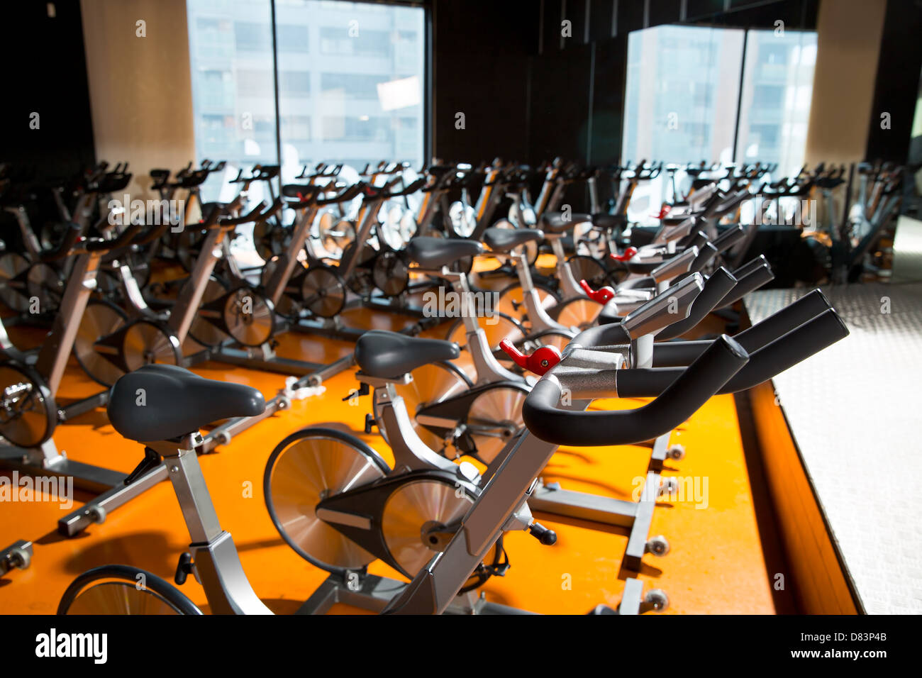 Aerobics spinning exercise bikes gym room with many in a row Stock Photo
