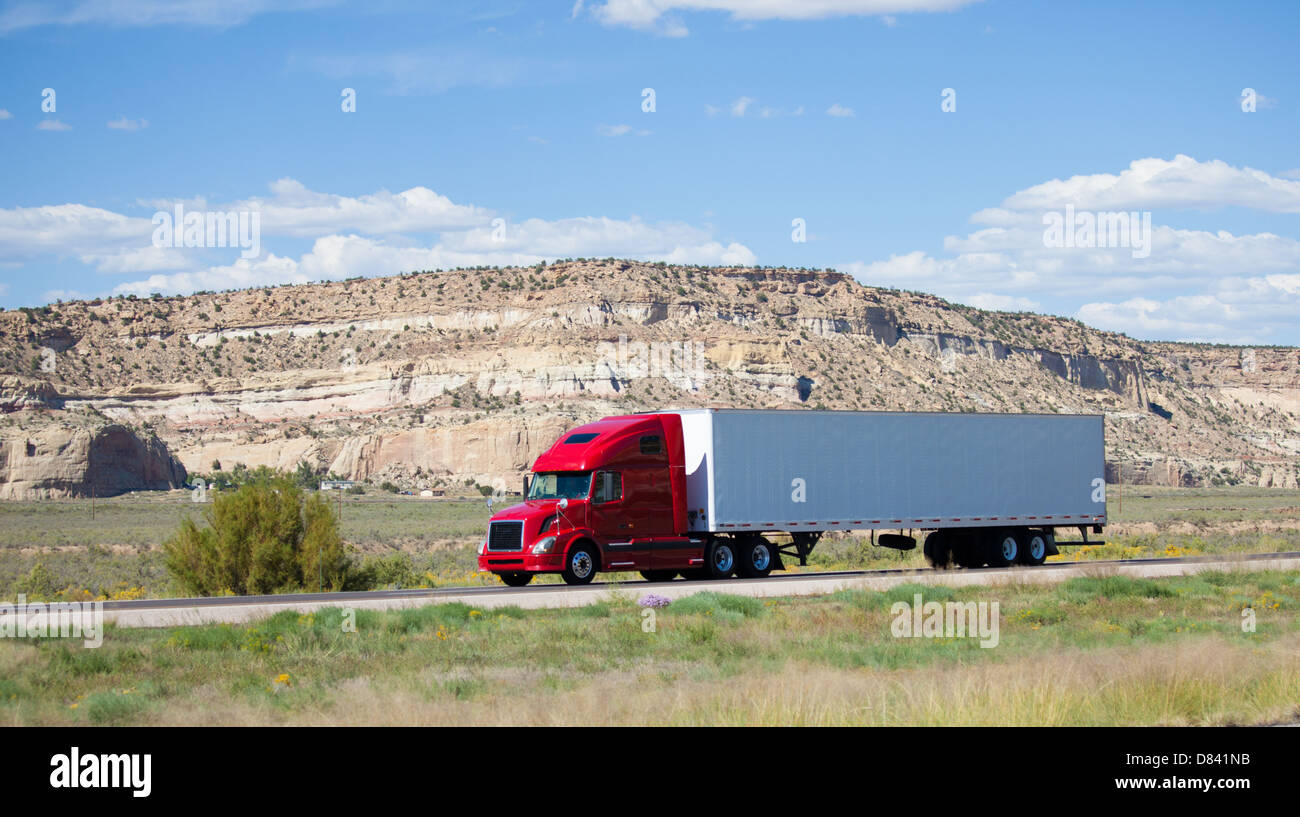 A semi-truck on the road in the desert Stock Photo