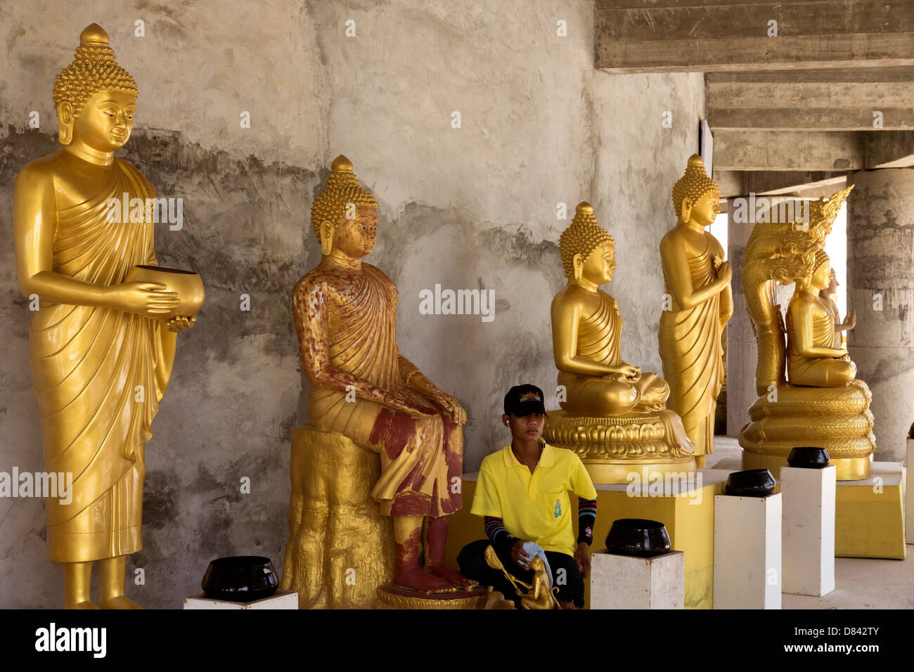 PHUKET, THAILAND FEBRUARY 15 2013: Groundskeeper cleans statues at Big Buddha Park in Phuket Stock Photo