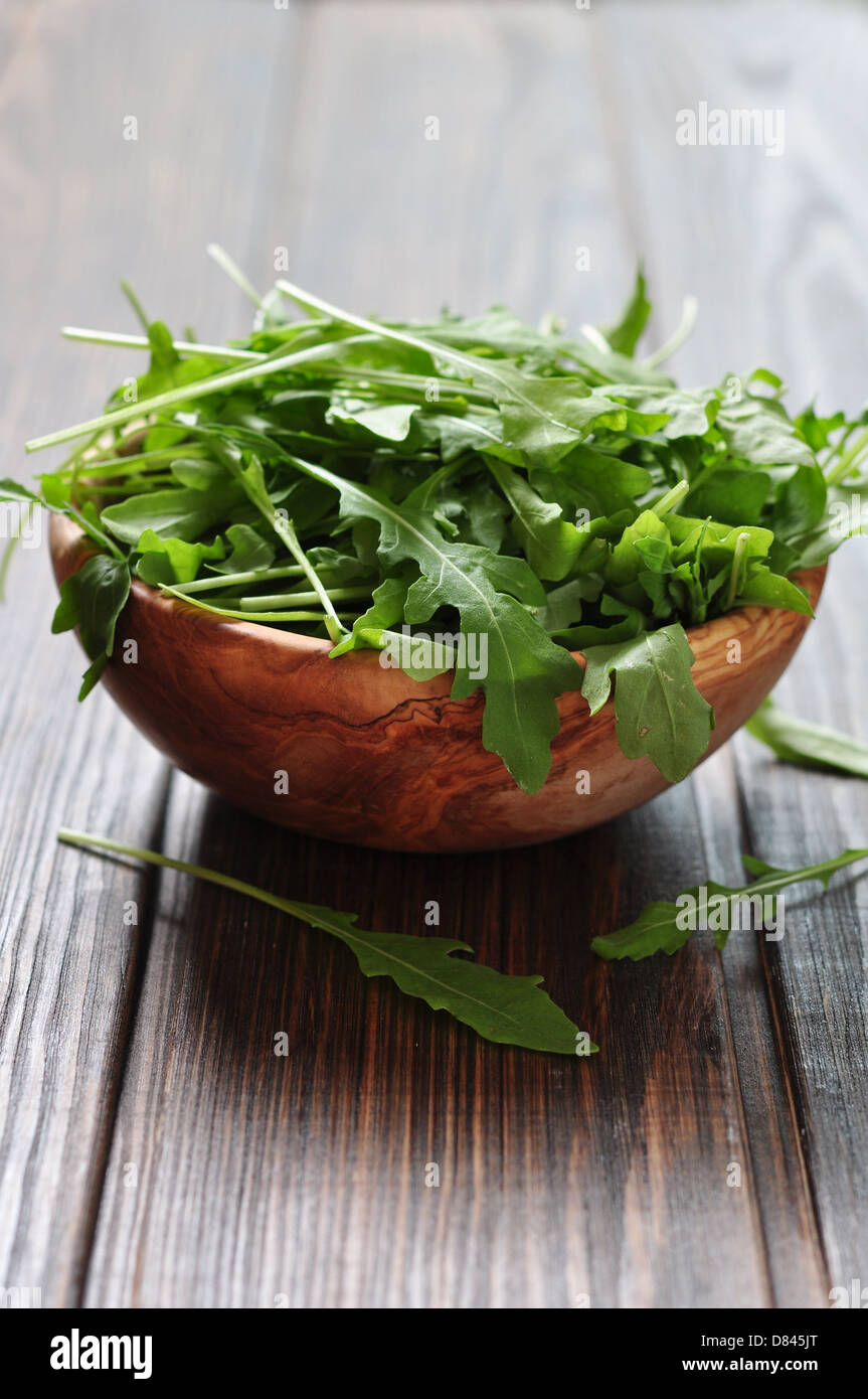 Fresh arugula leaves in wooden bowl on a wooden background Stock Photo