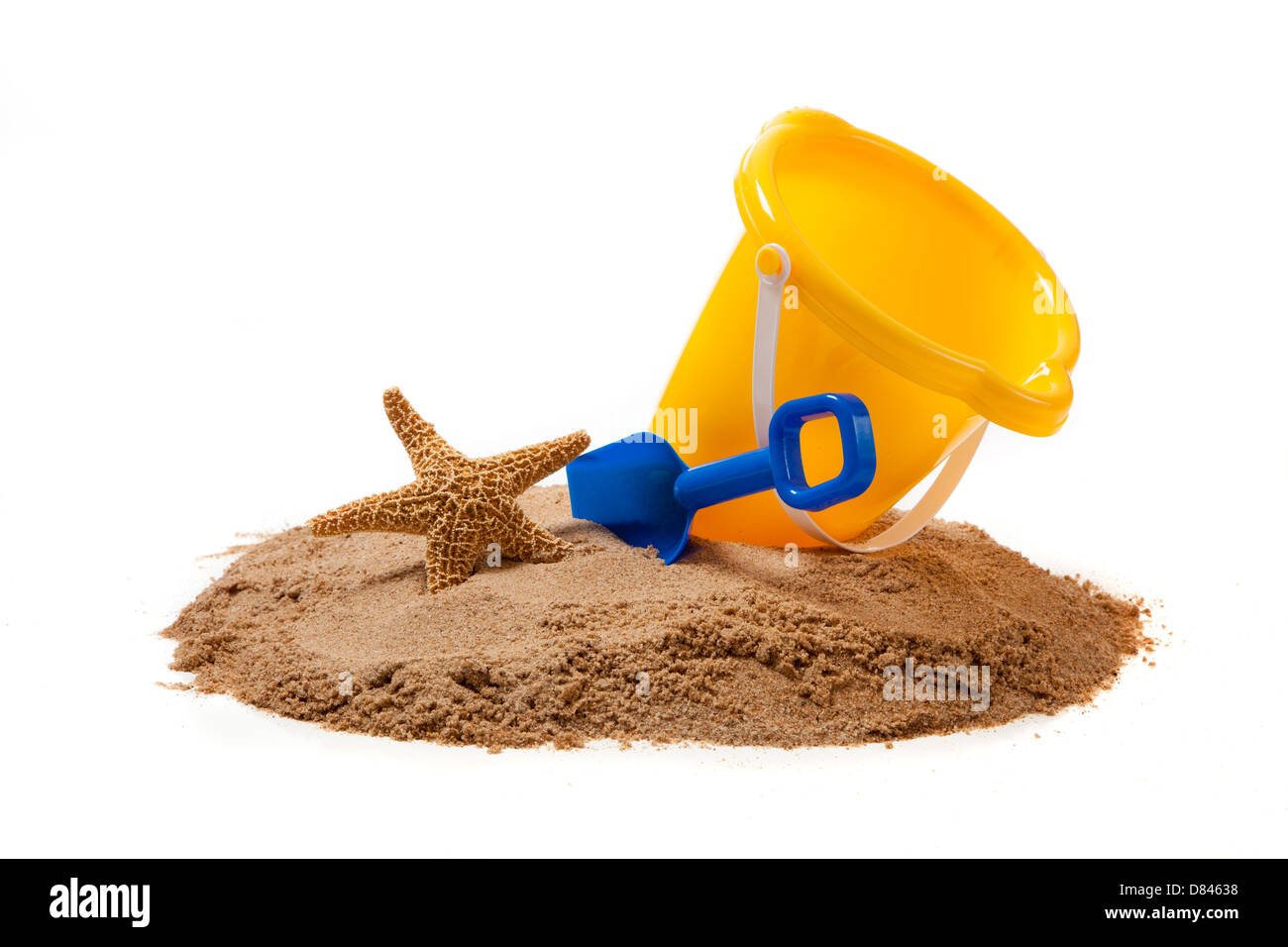 A yellow pail, blue shovel and a starfish on sand on a white background with copy space Stock Photo