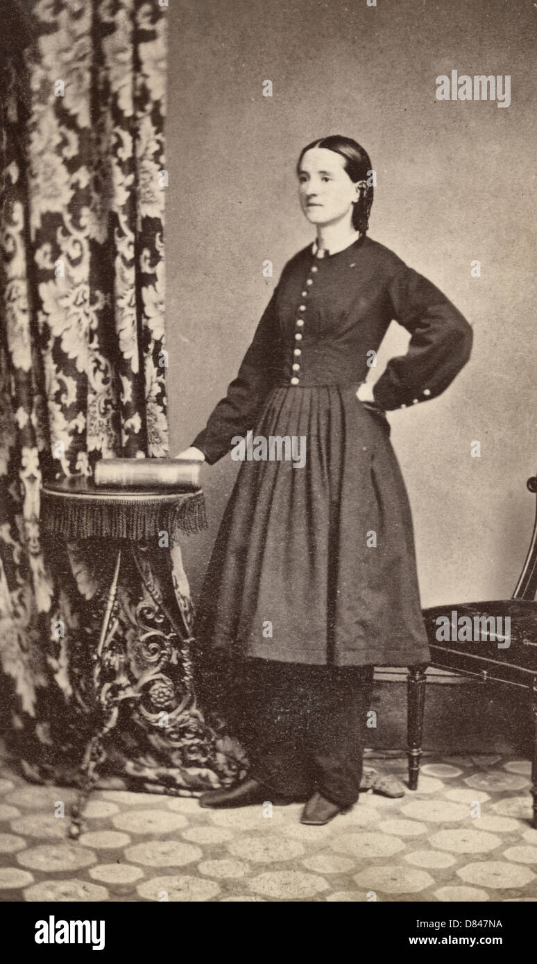 Civil War surgeon Mary E. Walker in a full-length studio portrait, facing left, hand resting on a book, circa 1865 Stock Photo