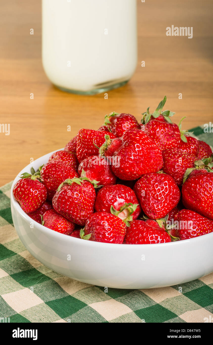 Bowl of fresh ripe strawberries with bottle of milk Stock Photo
