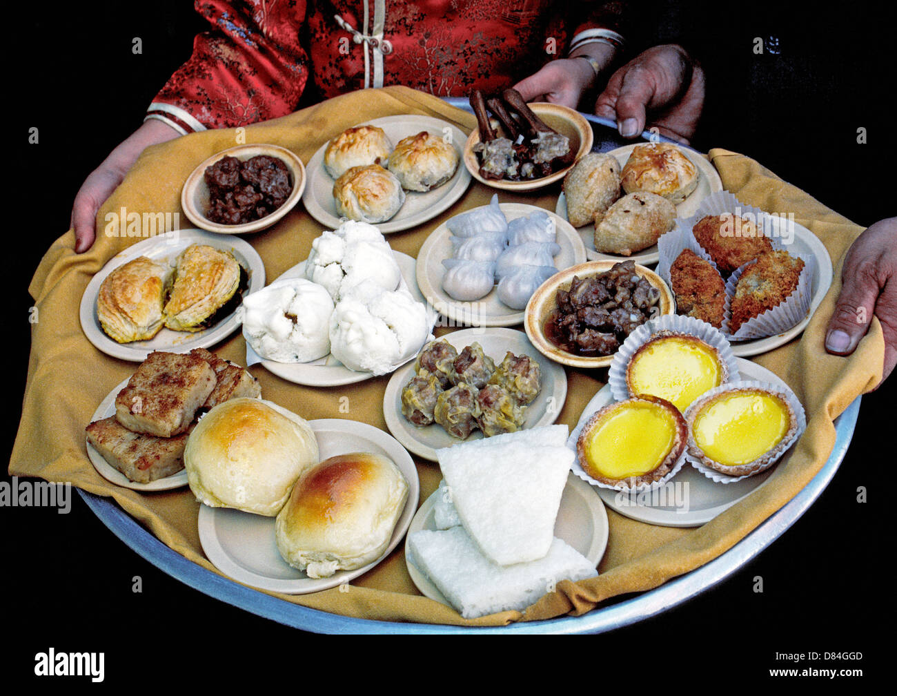 Various Chinese dishes of tasty Cantonese dim sum are served from a large food tray in a Chinatown restaurant in Los Angeles, California, USA. Stock Photo