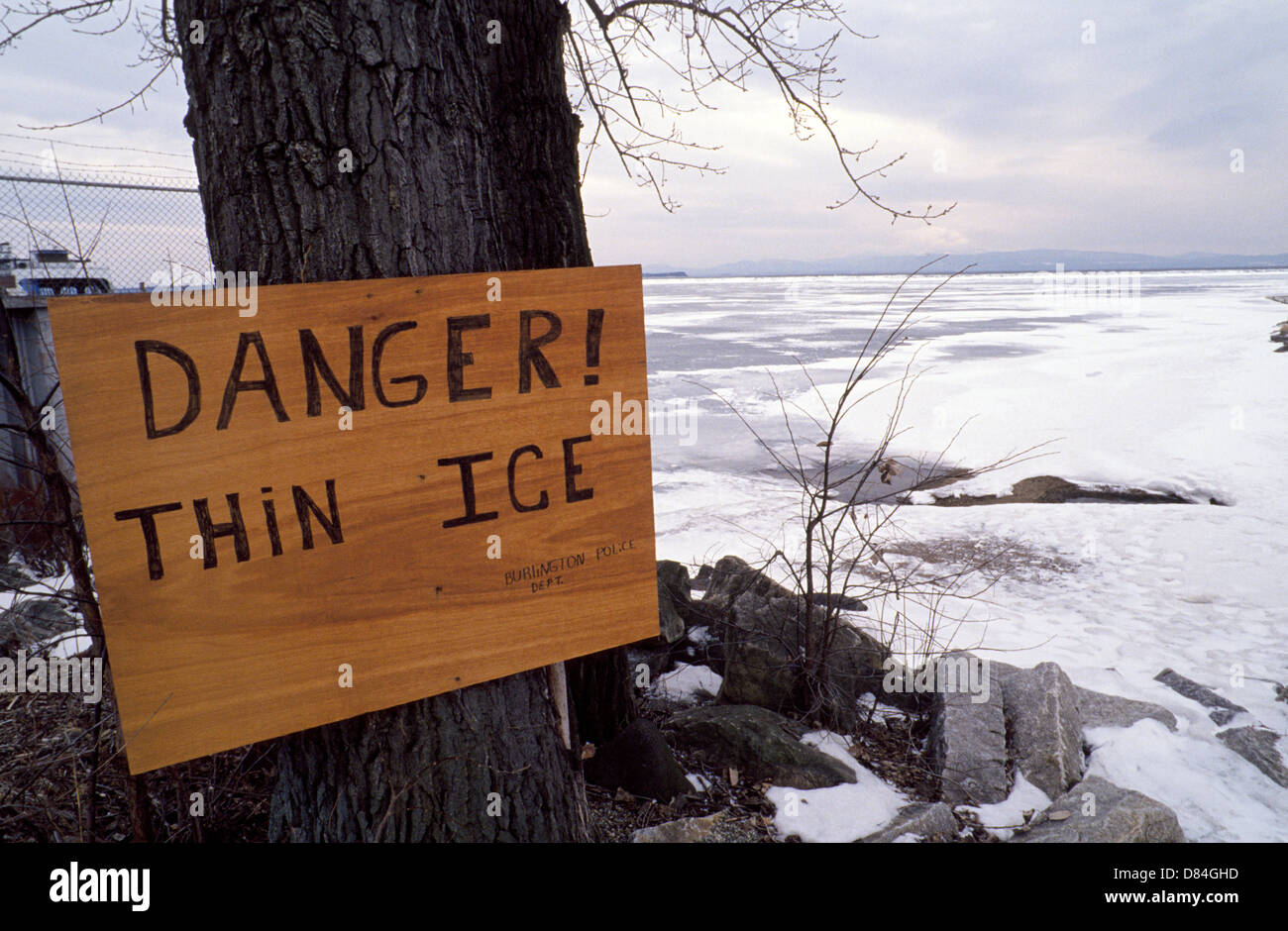 A handmade wooden police sign gives a DANGER! warning to residents and visitors to stay off the THIN ICE of Lake Champlain in Burlington, Vermont, USA Stock Photo