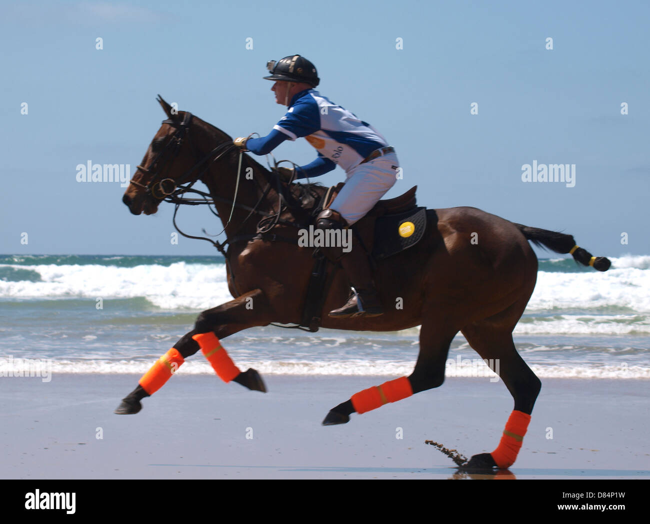 Polo player riding horse along beach, Watergate Bay, Cornwall, UK 2013 Stock Photo