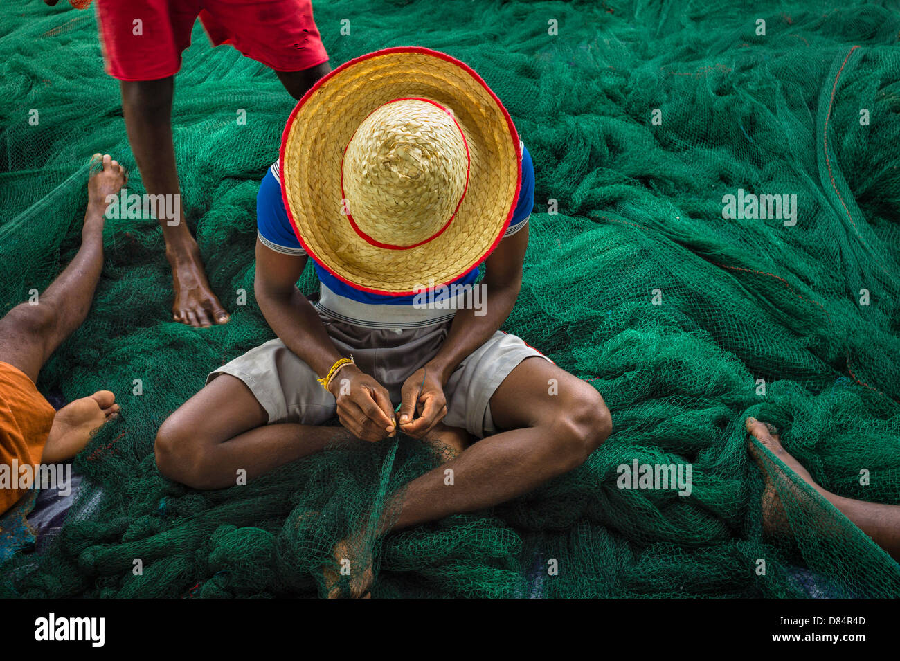 Fishermen use traditional tools to repair large fishing net at Mapilla