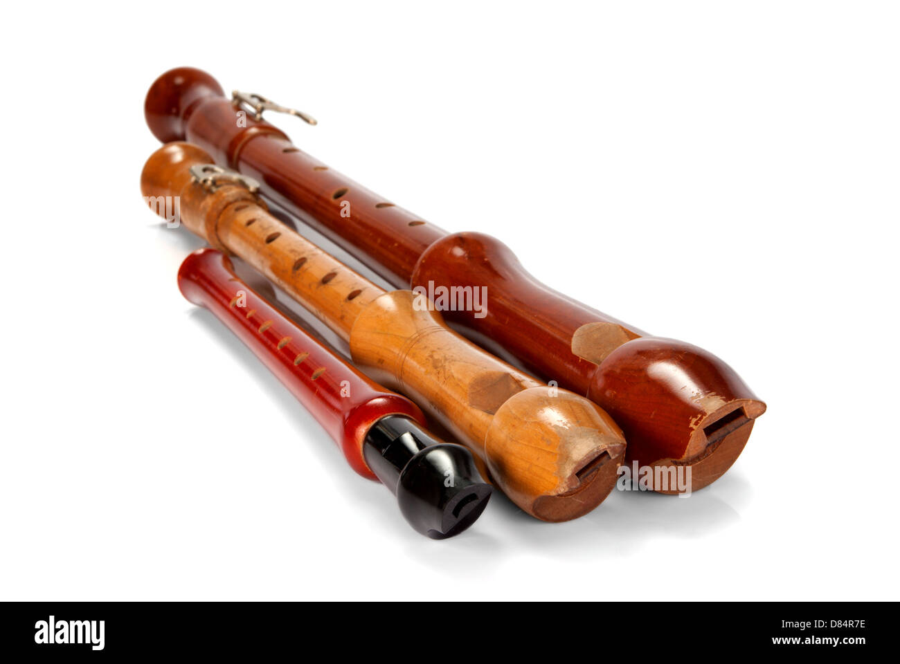 Three old battered wooden recorders isolated on white background Stock