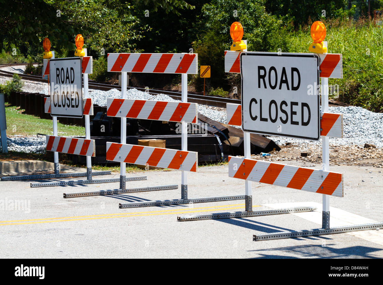 A trio of reflective road closed MUTCD type III spec barricades. Maintenance was being done to the railroad track crossing. Stock Photo