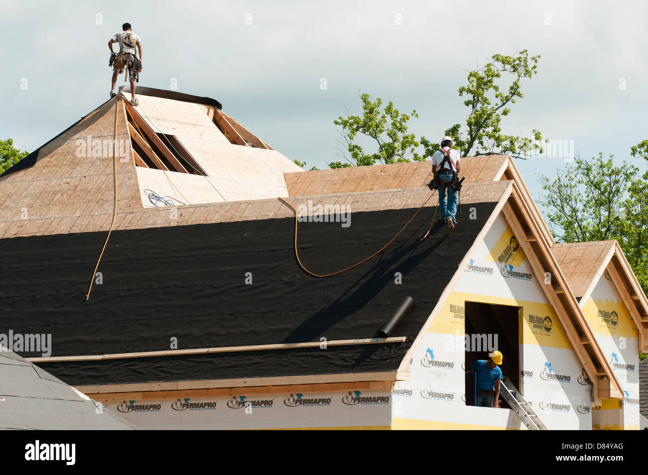 Construction workers roofing roof of new residential home. Stock Photo