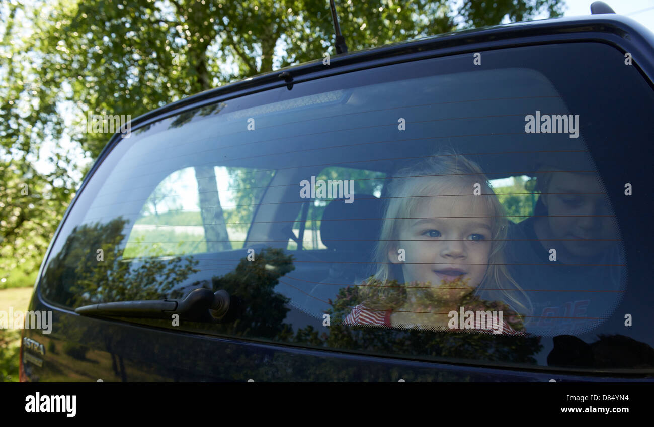 Child toddler girl in the car looking out through rear car door window Stock Photo