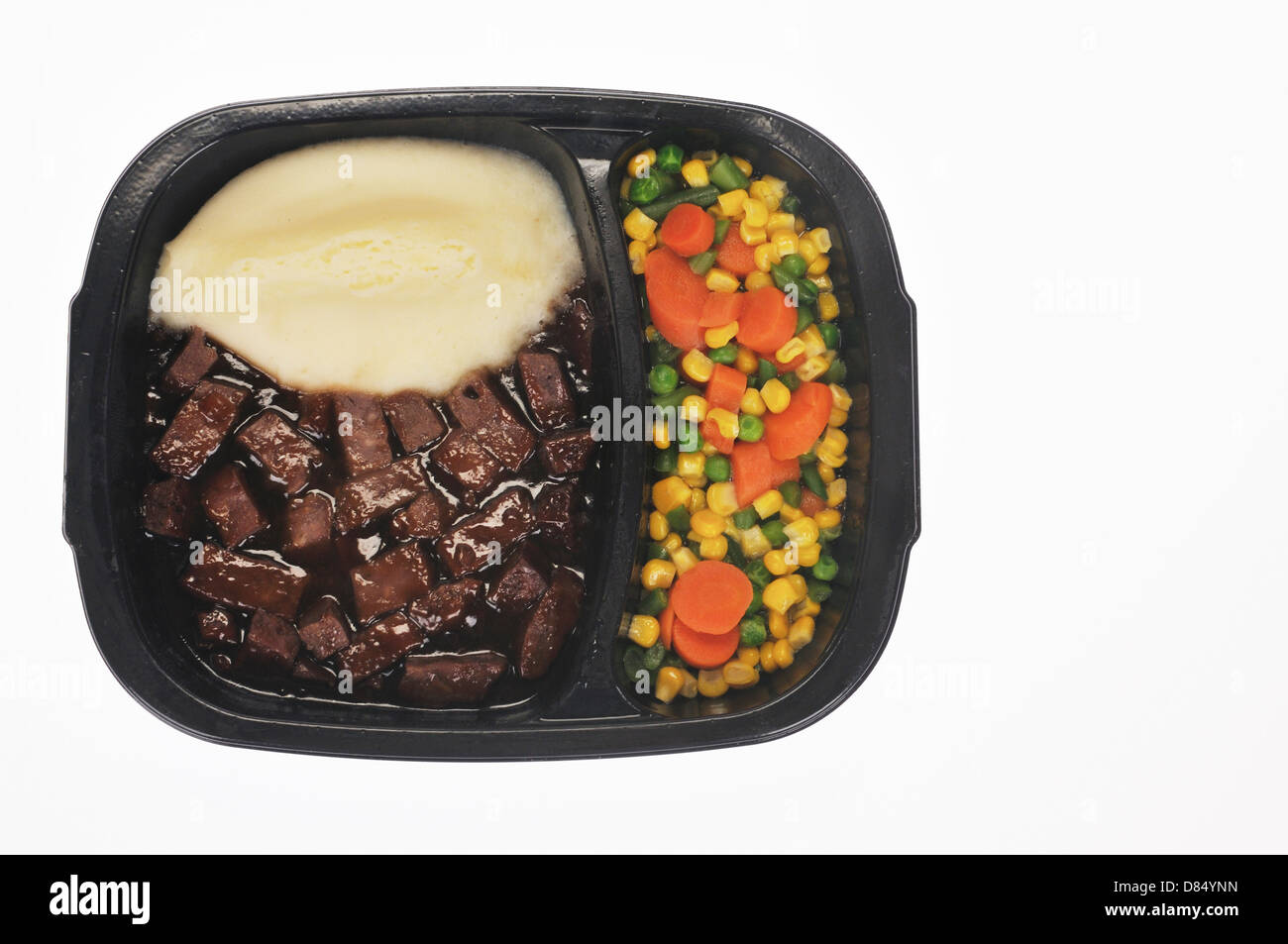 Cooked frozen tv dinner with mixed vegetables, mashed potatoes and beef tips on white background cutout, USA. Stock Photo