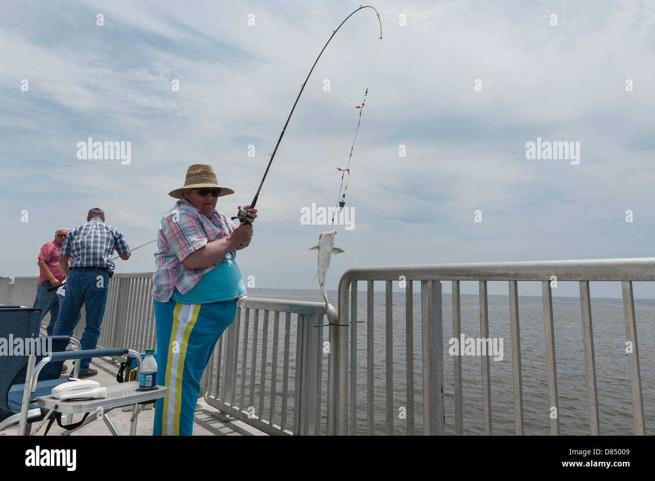 Woman reeling in a fish on the public pier at Cedar Key Florida on the Gulf coast Stock Photo