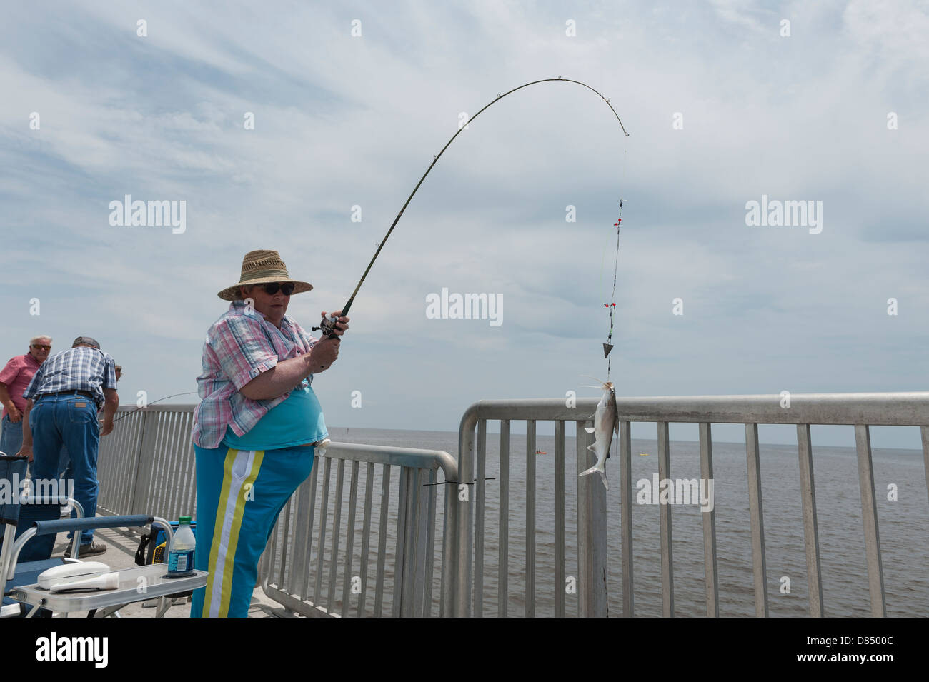 Woman reeling in a fish on the public pier at Cedar Key Florida on the