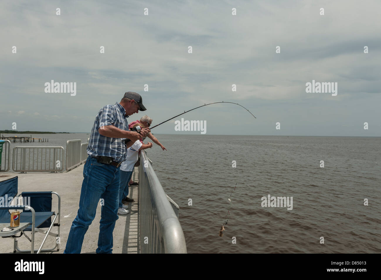 Man reeling in a fish on the public pier at Cedar Key Florida on the Gulf coast Stock Photo