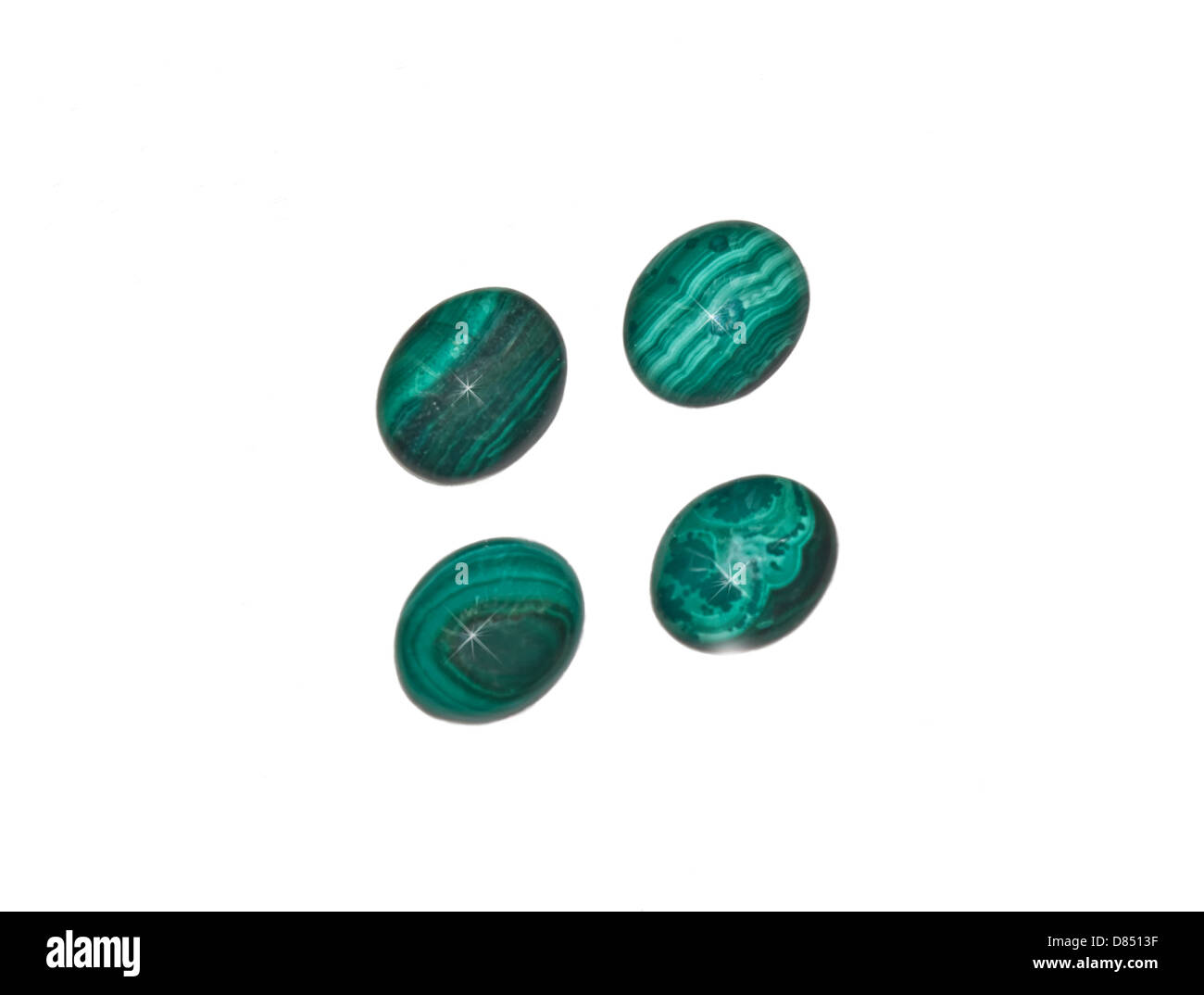 4 oval shaped malachite gems, isolated on a white background. It is a copper carbonate hydroxide mineral noted by its green band Stock Photo