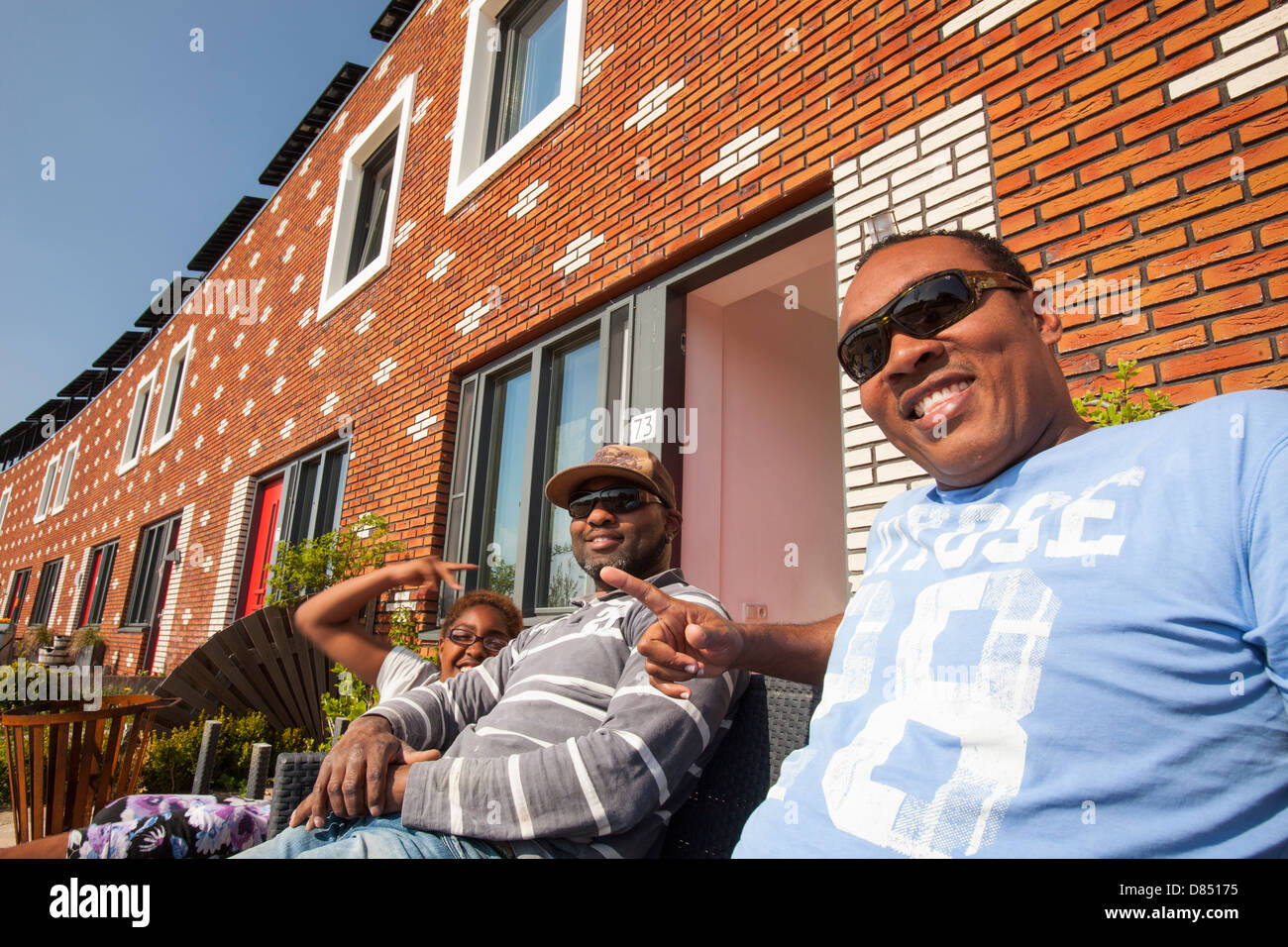 A family in front of their house in Almere with solar PV panels on the roof. Stock Photo