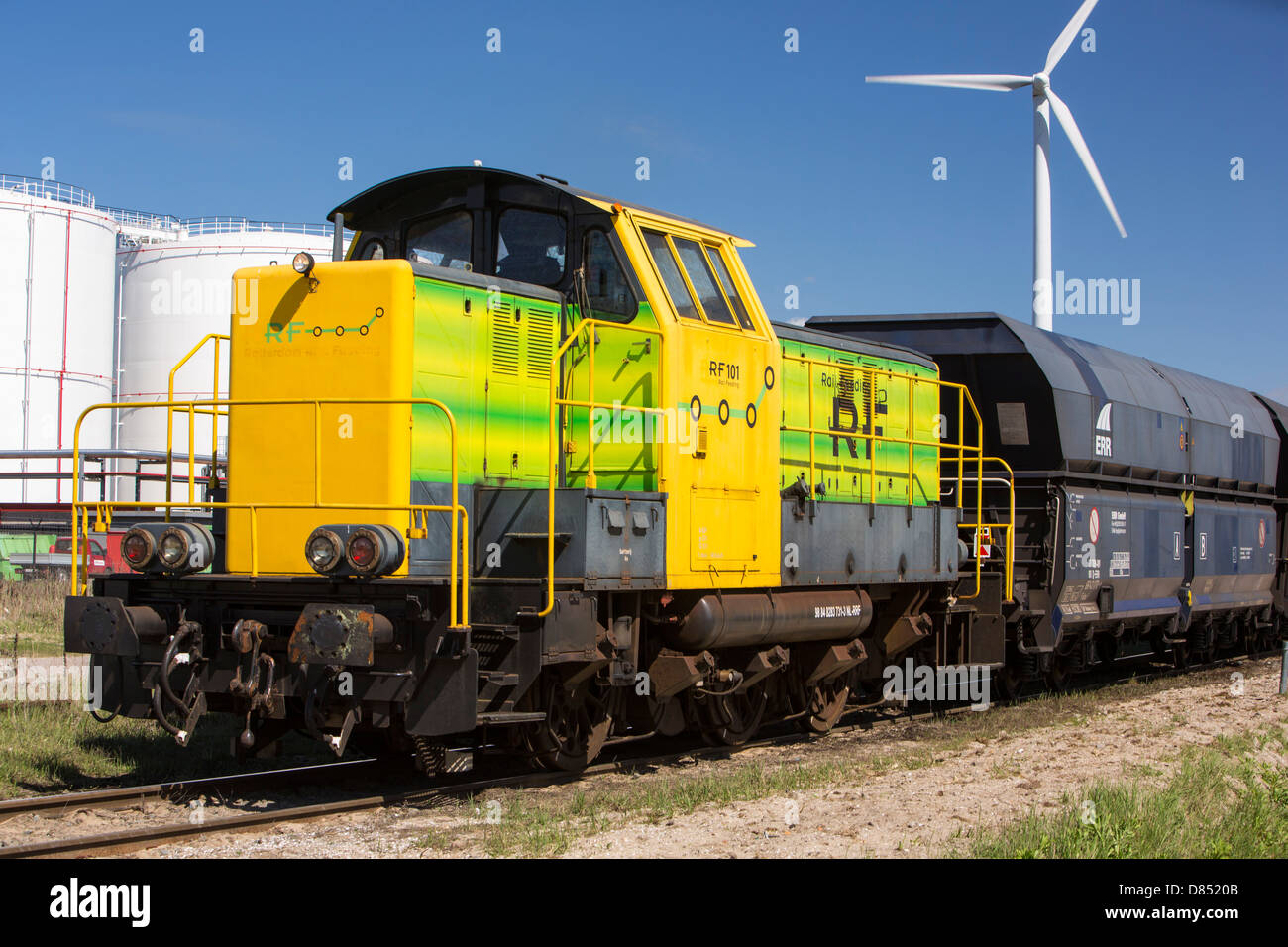 Climate change heaven and hell, a train infront of an oil terminal in Amsterdam, Netherlands, with wind turbines Stock Photo