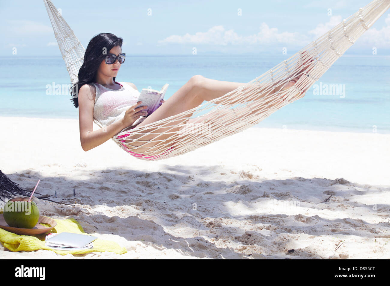 young woman lying in hammock reading book Stock Photo - Alamy