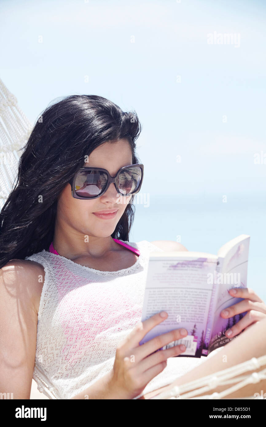 young woman lying in hammock reading book Stock Photo - Alamy