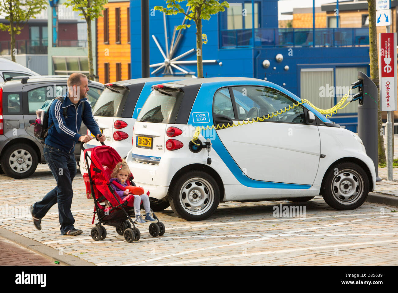 A Smart car electric car at a charging station for electric cars in Ijburg, Amsterdam, Netherlands, in front of floating houses. Stock Photo