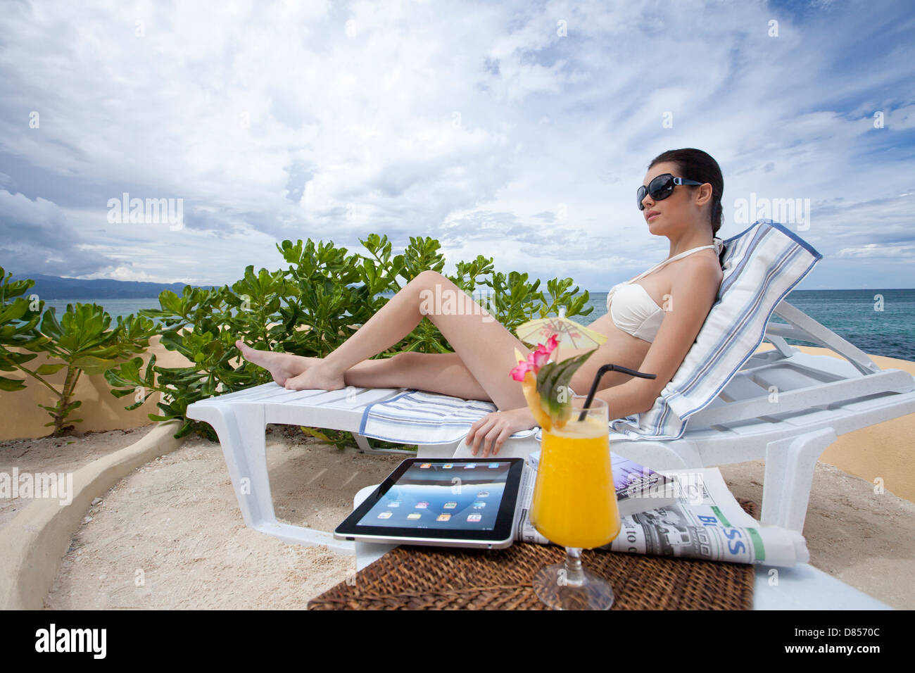young woman sunbathing in deck chair ocean. Stock Photo