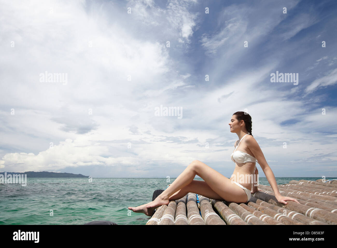 young woman sitting on dock ocean. Stock Photo