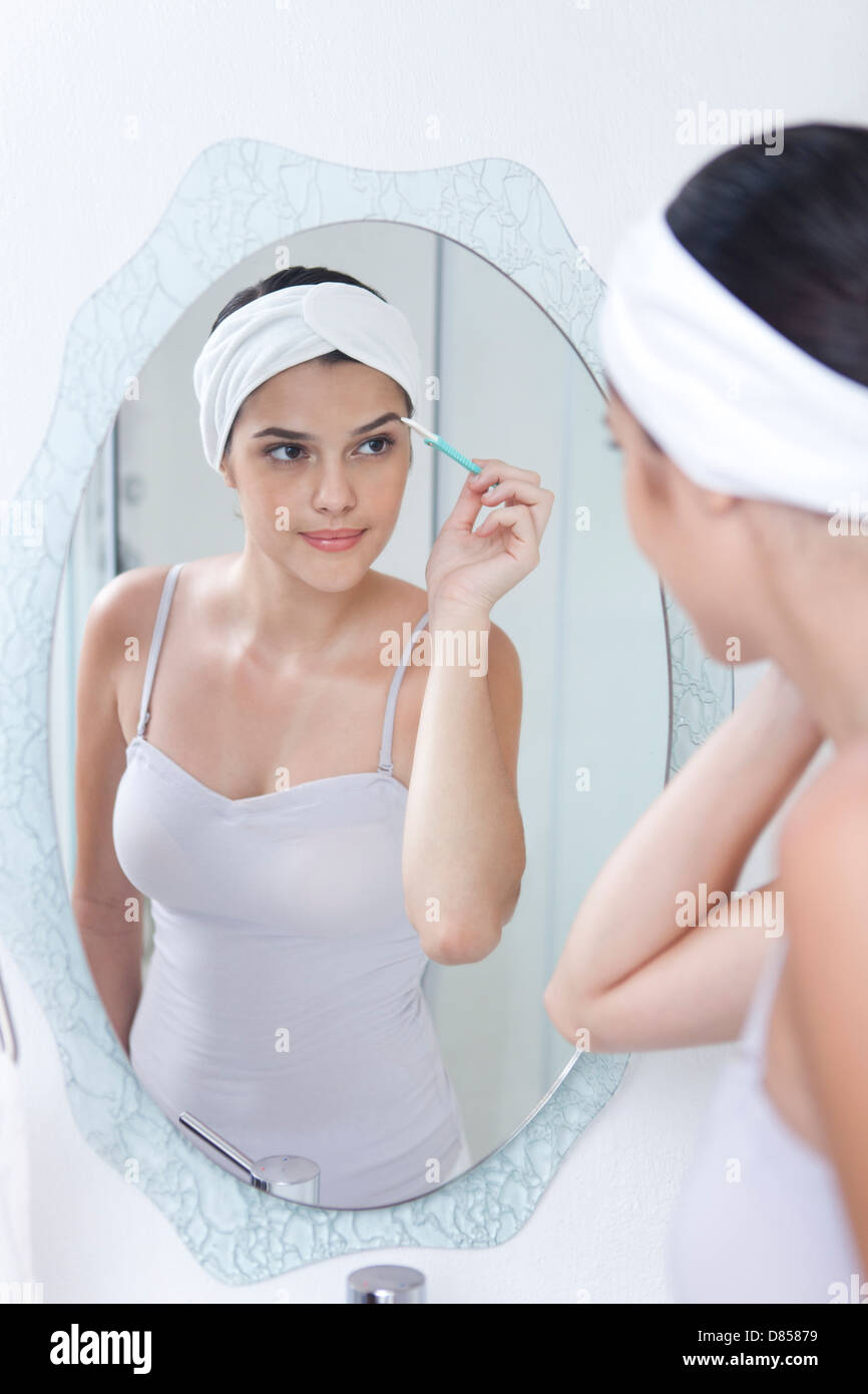 young woman tweezing her eyebrows Stock Photo Alamy