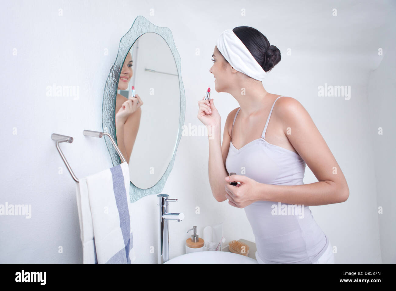young woman looking into mirror applying make up. Stock Photo