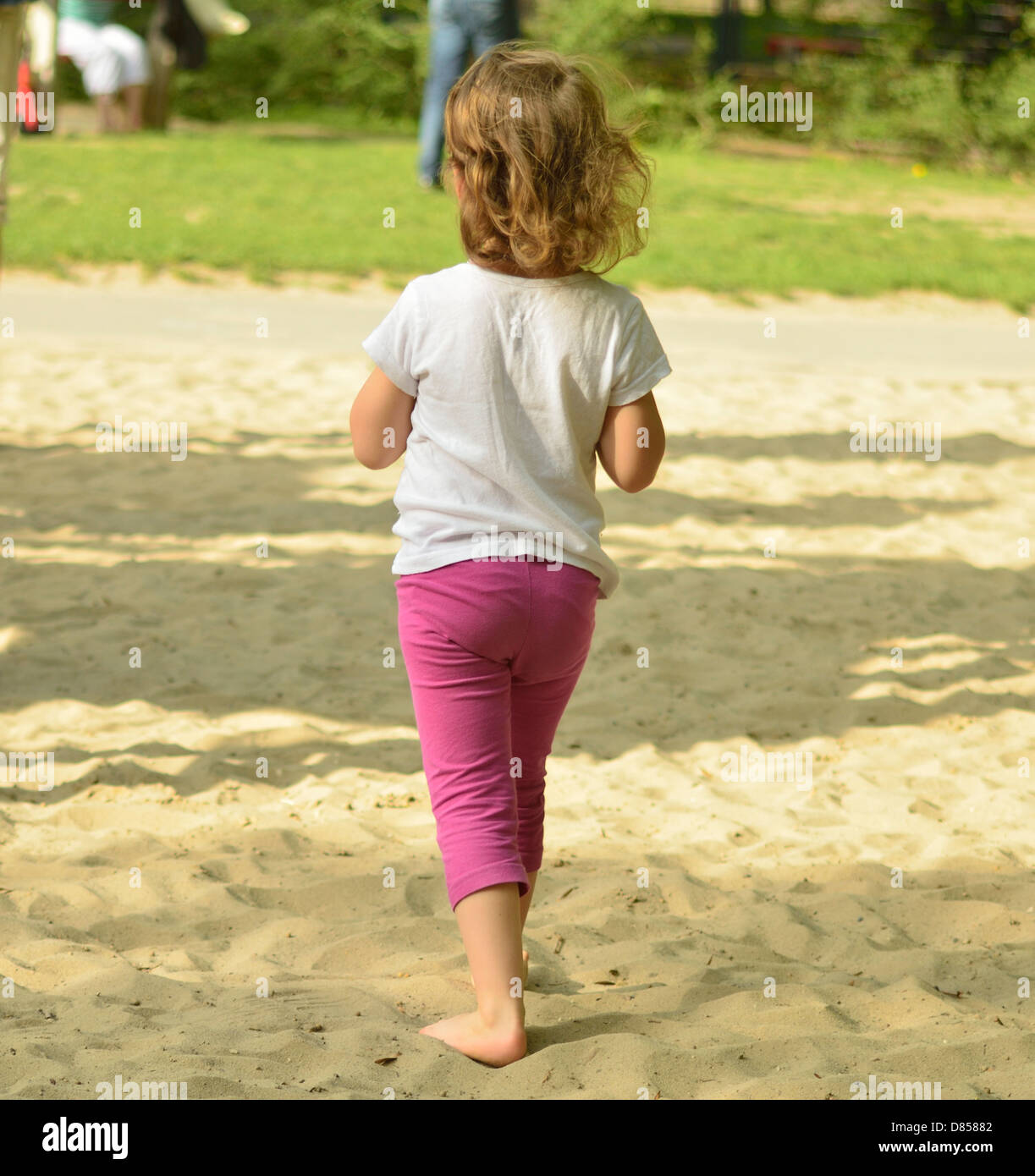 4 year old little girl walks in the sand on playground barefoot Stock Photo