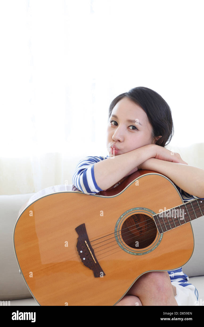 young woman sitting on sofwith acoustic guitar Stock Photo - Alamy