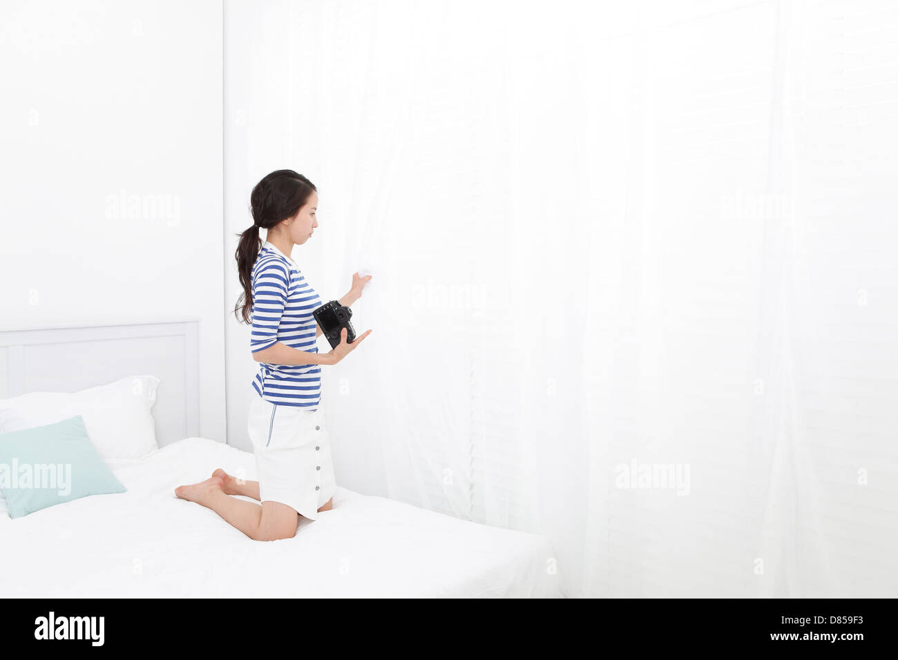 young woman on bed holding camera. Stock Photo