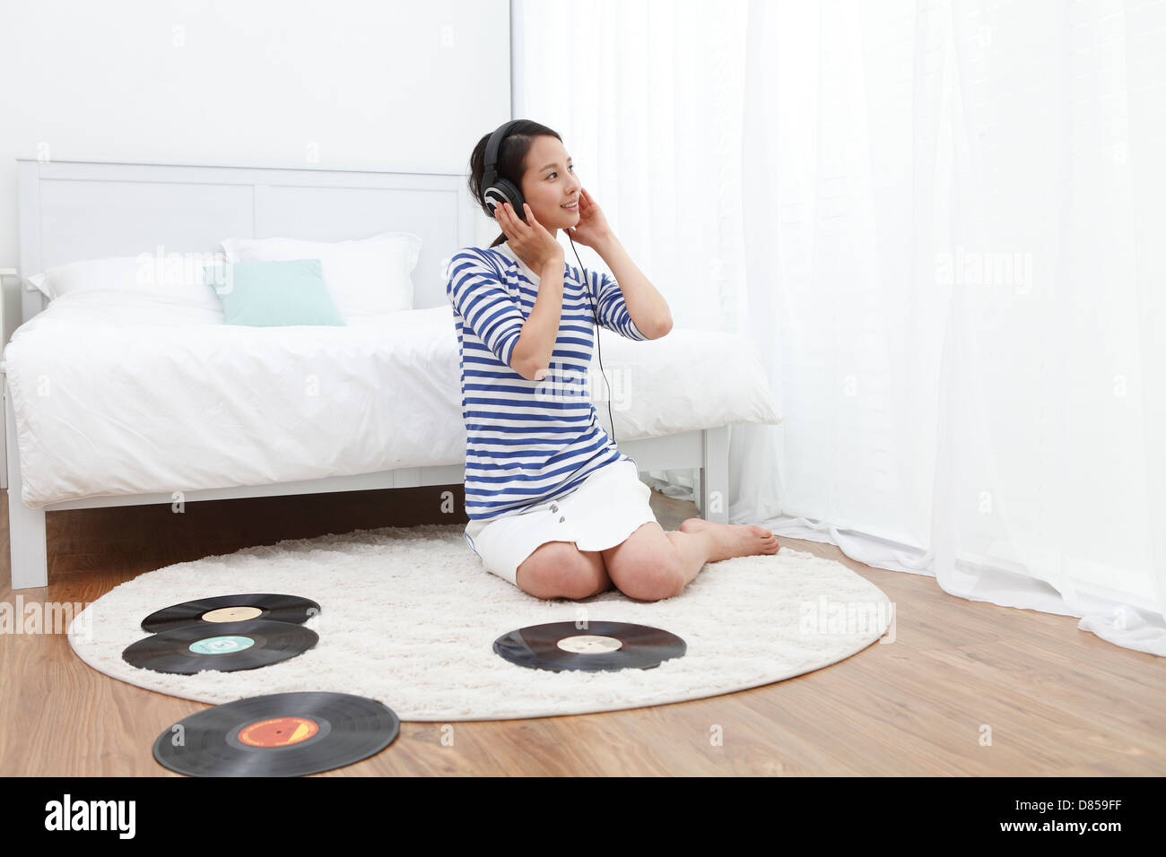 young woman sitting on floor listening to records. Stock Photo