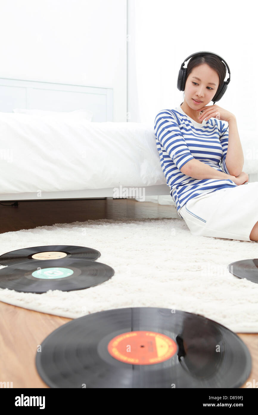 young woman sitting on floor listening to records Stock Photo - Alamy