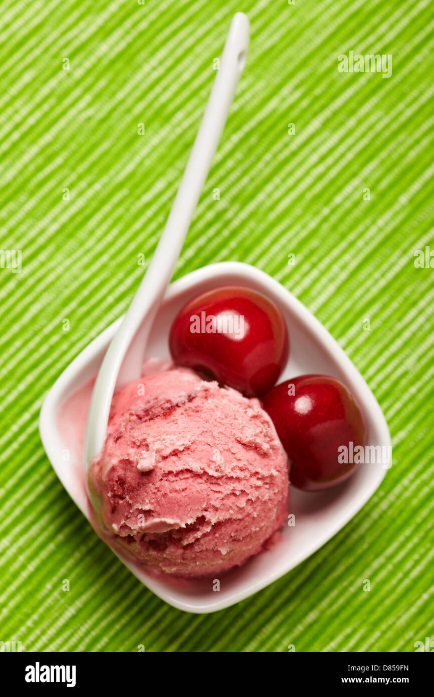 A scoop of cherry ice cream with spoon and cherries Stock Photo