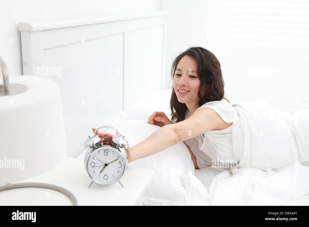 young woman turing off alarm clock. Stock Photo