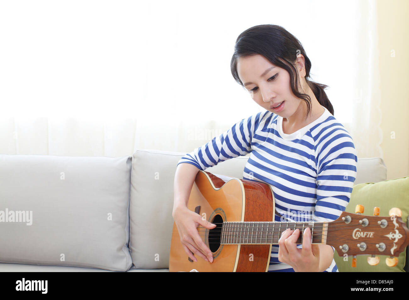 young woman sitting on sofwith acoustic guitar Stock Photo - Alamy