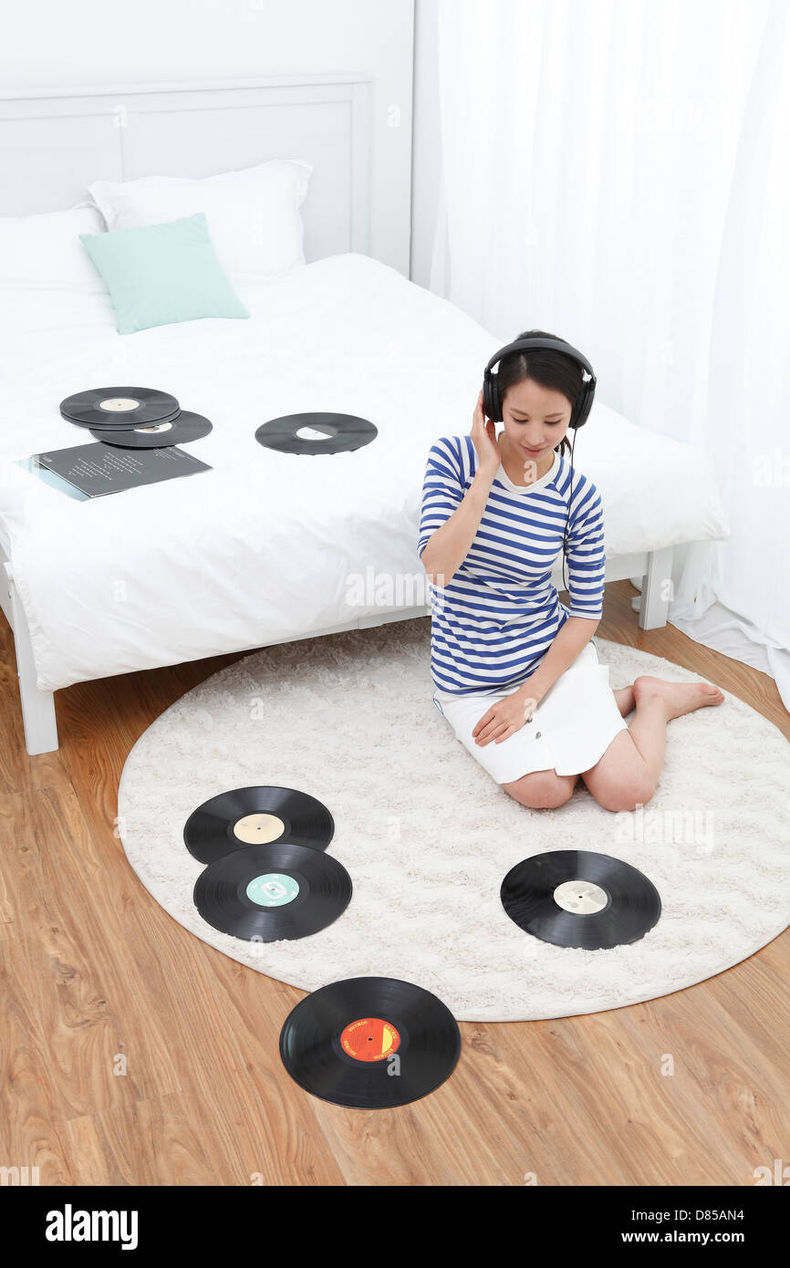 young woman sitting on floor listening to records Stock Photo - Alamy