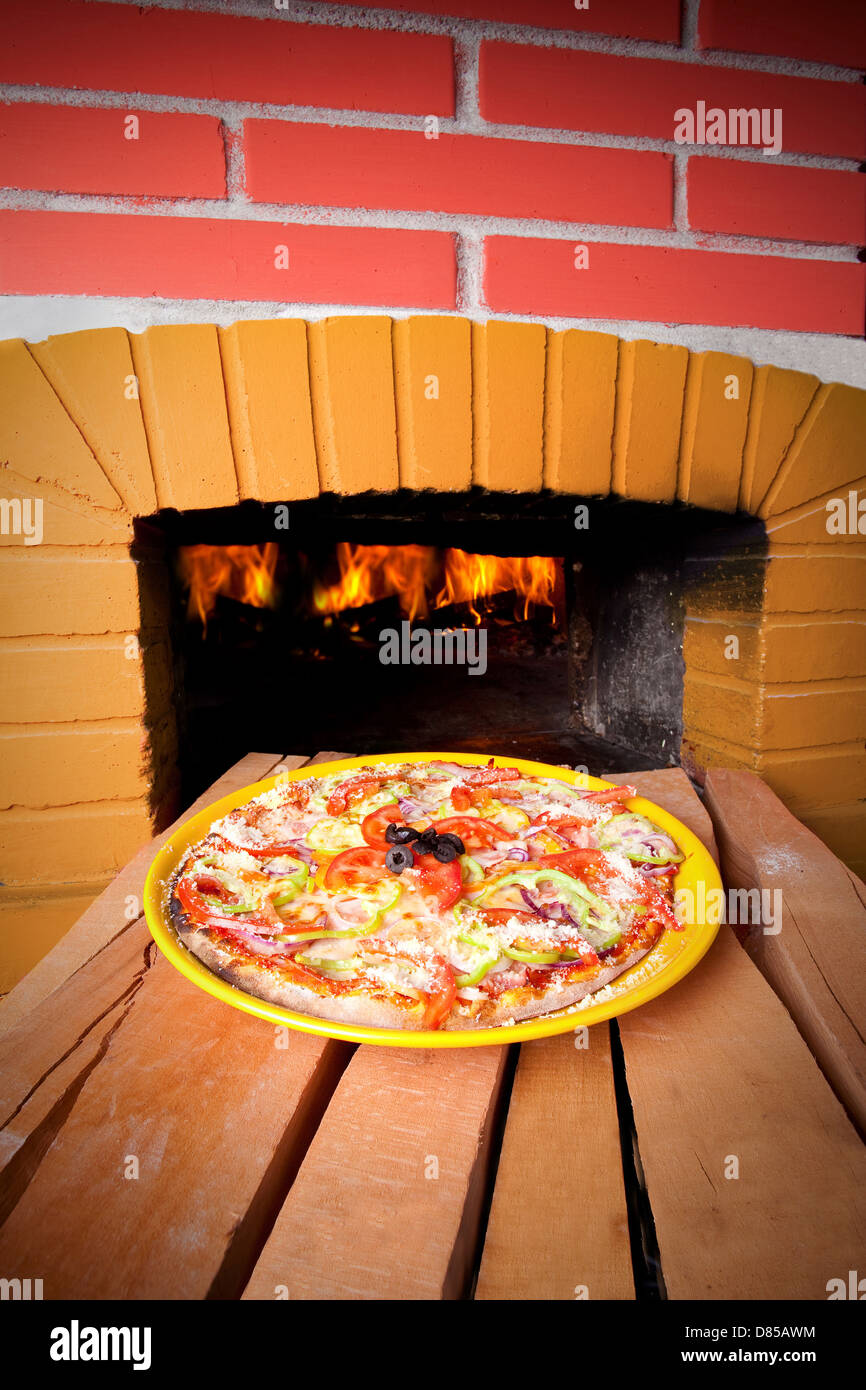 Pizza baking with wood fire in the oven Stock Photo