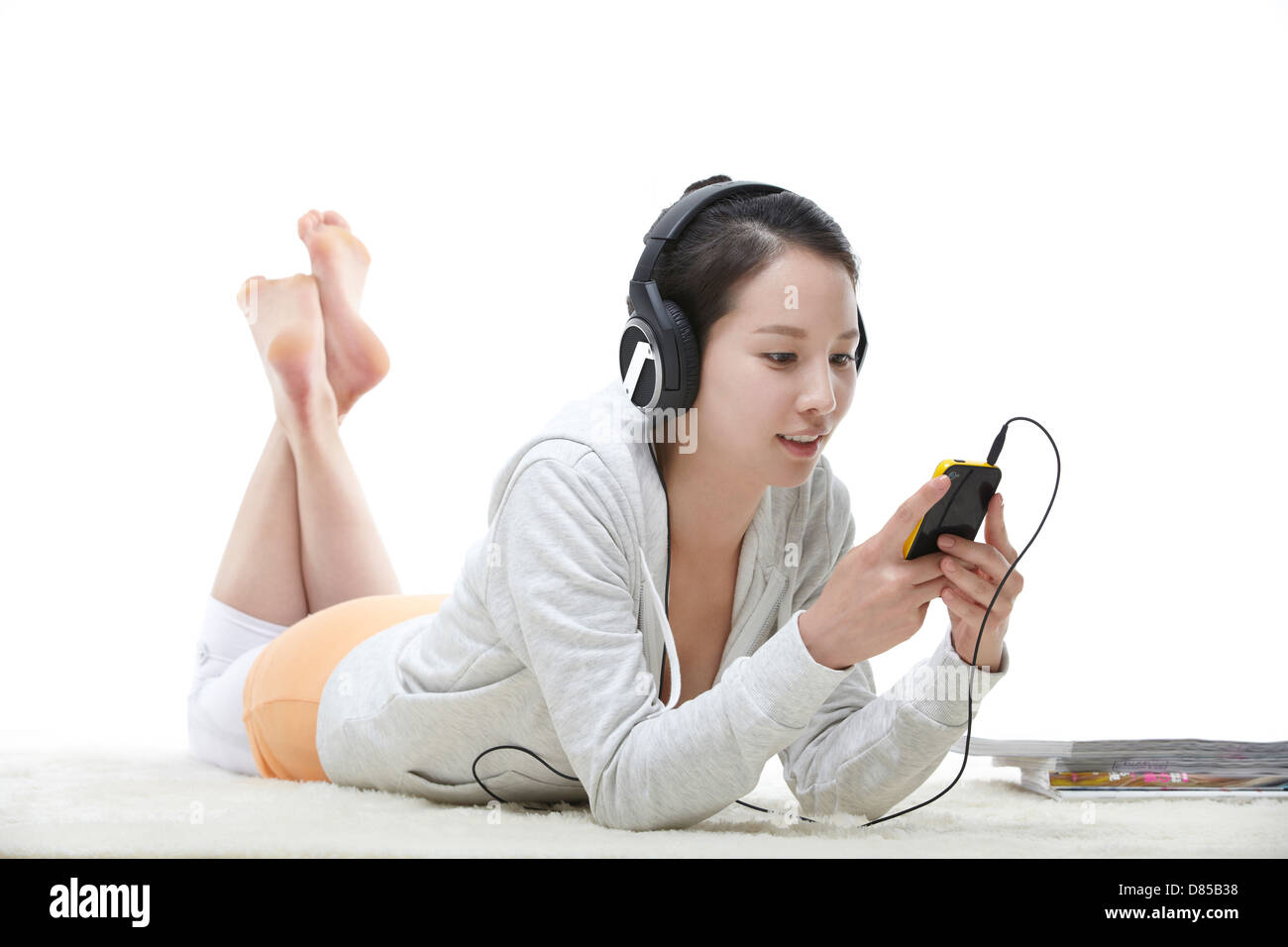 young woman lying on her front listening to music Stock Photo - Alamy
